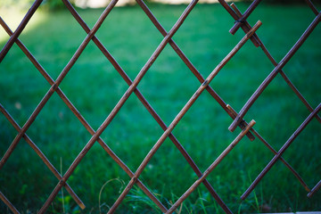 Background bamboo net on green grass background. Outdoor decoration of the cottage, wooden grid, texture with diamonds in eco-color