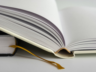 Opened blank hardcover book with ribbon bookmark. Isolated closeup on a white background.