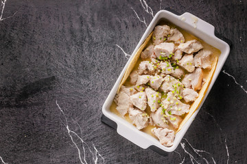 Stewed white meat of turkey in a creamy sauce with herbs and seasonings in a ceramic bowl. Top view. Copy space
