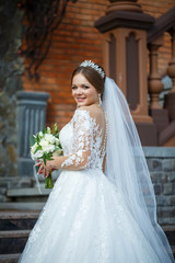 Naklejka premium bride in a white dress with a bouquet in her hands and a crown on her head