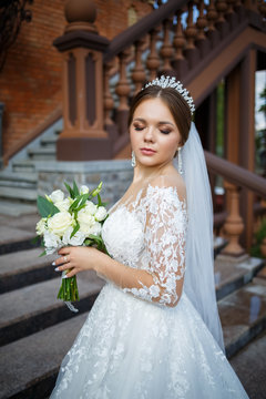 bride in a white dress with a bouquet in her hands and a crown on her head