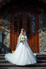 Fototapeta premium bride in a white dress with a bouquet in her hands and a crown on her head