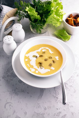 Vegetable cream soup with cream and pumpkin seeds in white plates. Healthy and tasty food. Vertical shot. Copy space