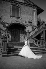 bride in a beautiful white and long dress on a background of a brick building