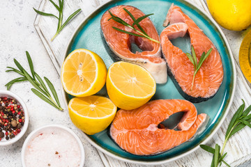Raw salmon steak on white top view.