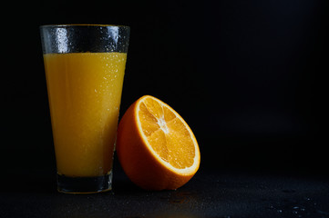 orange juice in a glass on a black background close-up