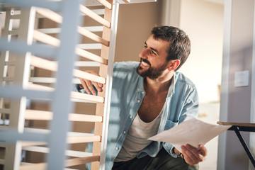 A man reading instructions for assembling baby crib.