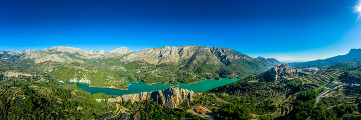 Panoramic view of popular Spanish vacation destination El Castell de Guadalest above a beautiful water reservoir with 2 castles and fortified enclave