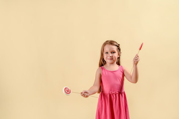 Portrait of beautiful joyful little long haired girl in a pink dress with candy isolated.A lot of...