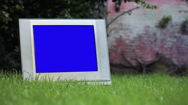 Old TV with Blue Screen over Green Grass. You can replace blue screen with the footage or picture you want. You can do it with “Keying” effect in After Effects or any other video editing software.