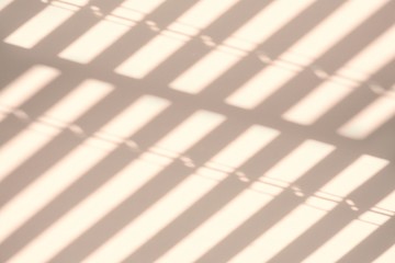 Light and shadows on a light wall through the window blinds. Diagonal parallel lines, abstract half frame composition. Copy space for text.