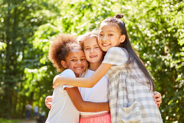 Three multicultural girls hug each other