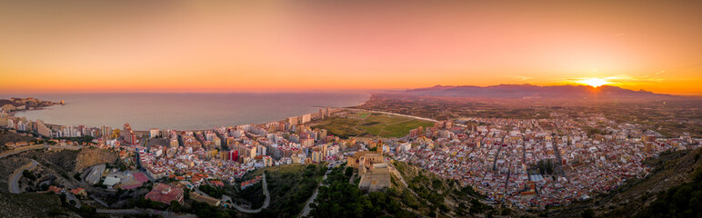 Aerial sunset view of Cullera church and castle with rectangular keep towering over the popular Spanish vacation resort town