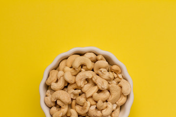 cashew nuts in a white ceramic bowl on a yellow background. the concept of proper nutrition and health. Healthy food and snack, organic vegetarian food. Walnuts, pistachios, almonds, hazelnuts