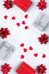 Gift boxes, bows and red hearts on a white background. Valentine's day concept, love, romance, congratulations, holiday. Top view, flat lay, vertical.