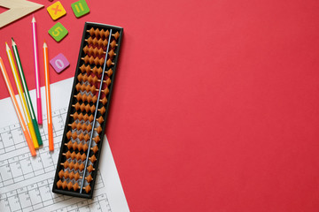 Mental arithmetic and math concept: colorful pens and pencils, numbers, abacus scores on red background, copy space - obrazy, fototapety, plakaty