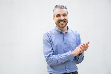 Smiling young man applauding. Handsome stylish guy clapping hands and looking at camera. Applause concept