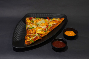 Paneer pizza on dark background, table top close-up, India