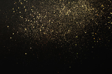 Gold glitter on black background. Holiday abstract texture