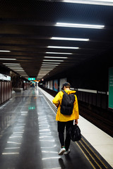 Obraz premium Tourists man with backpack waiting the train in metro. Passenger person waiting on platform underground station. Travelling, lifestyle, adventure, concept.
