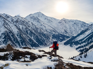 A traveler meets dawn on a mountain lake in winter