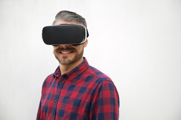 Smiling young man wearing VR glasses. Front view of cheerful guy with new modern device. Technology concept