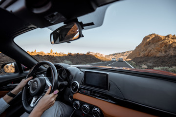 Woman driving car on the desert road, close-up view focused on the steering wheel and hands....