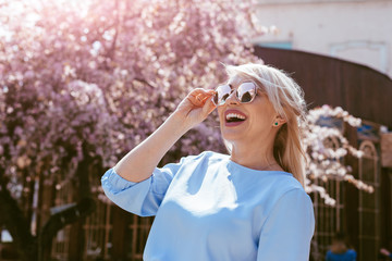 Beautiful model in blue dress by spring blooming tree