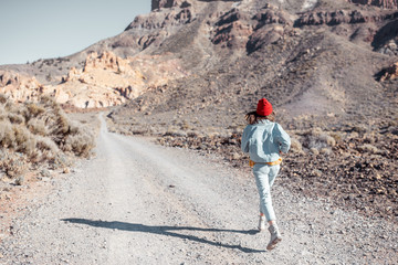 Lifestyle portrait of a carefree woman dressed casually in jeans and red hat enjoying travel on the desert valley