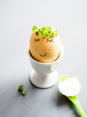 Weichgekochtes Ei mit aufgemalten Gesicht in einem weißen Eierbecher. Gesundes Frühstück, Humor