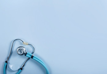 Blue medical stethoscope on a blue background, top view, copy space