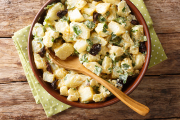 Morocco cuisine potato salad with yogurt, herbs, spices and dried olives close-up in a bowl....