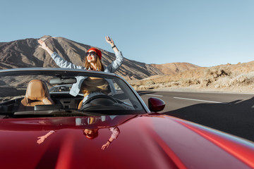 Carefree woman dressed casually in jeans and red hat enjoying road trip on the volcanic valley,...