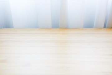 Wooden table in light brown color place against white curtain by the window with soft natural light. For background and texture.