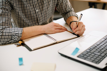 Businessman taking note. Close up of male hand writing business plan. 
