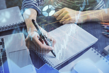 Financial chart drawn over hands taking notes background. Concept of research. Double exposure