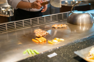 Japanese chef cooking meat in teppanyaki restaurant