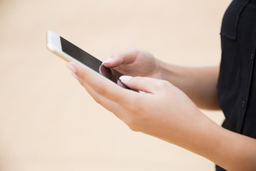 Cropped shot of woman using smartphone. Close-up partial view of woman standing on street and using mobile phone. Technology concept
