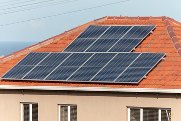 A close up view of solar pannels on top of a house roof in the main city