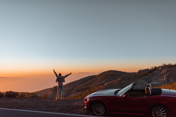 Landscape view on the roadside above the clouds with woman enjoying beautiful sunset while...