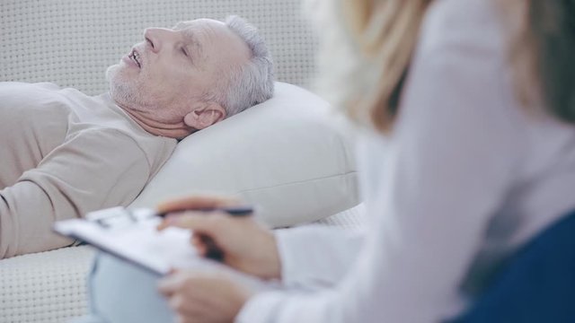 selective focus of mature man lying on couch and talking to psychologist