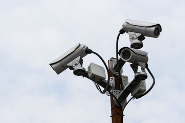A group of surveillance cameras on a sky background.