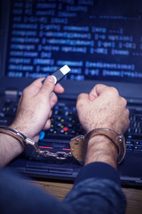 Hands of a hacker in handcuffs holding USB. Prisoner or arrested terrorist in handcuffs, selective...