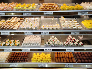 traditional Indian sweets kept in the fridge of a decorated mithai shop. Desserts like Laddoo, Barfi, and other dry fruits like cashew are gifted in festivals and weddings are on display