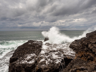 Wave crashes on stone coast line, West coast of Ireland, Dark stormy cloudy sky.