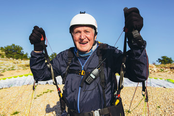 Active senior paraglider on the ground prepairs to fly.