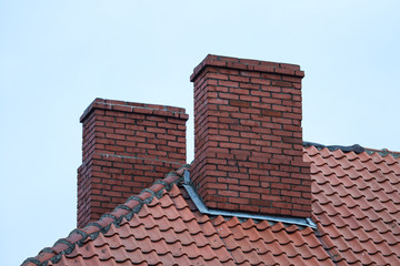 House roof view of two chimneys in cloudy overcast day.