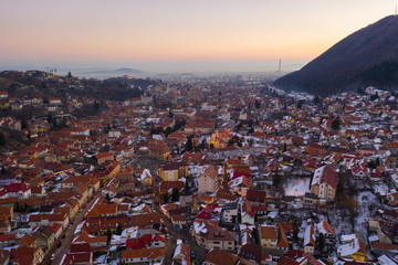 Aerial drone shot of Brasov old town at sunrise on a beautiful winter morning
