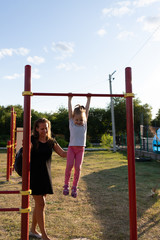 Fototapeta premium A small child goes in for sports in the stadium. hanging on the horizontal bar, on the uneven bars