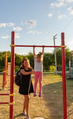 Fototapeta premium A small child goes in for sports in the stadium. hanging on the horizontal bar, on the uneven bars